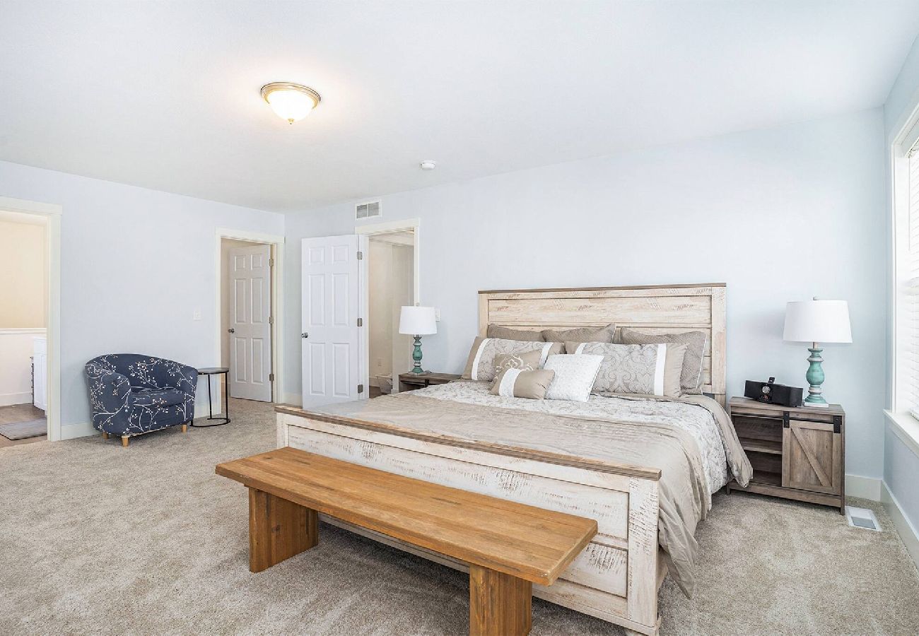 Primary bedroom with a king bed, wooden bench, nightstands, and walk-in closet