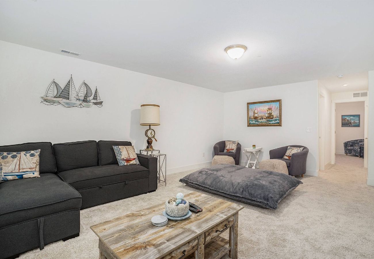 Basement living area with sectional sofa, accent chairs, and oversized floor pillow