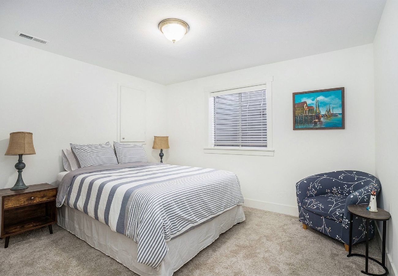 Basement bedroom with queen bed, sitting area, and night stand 