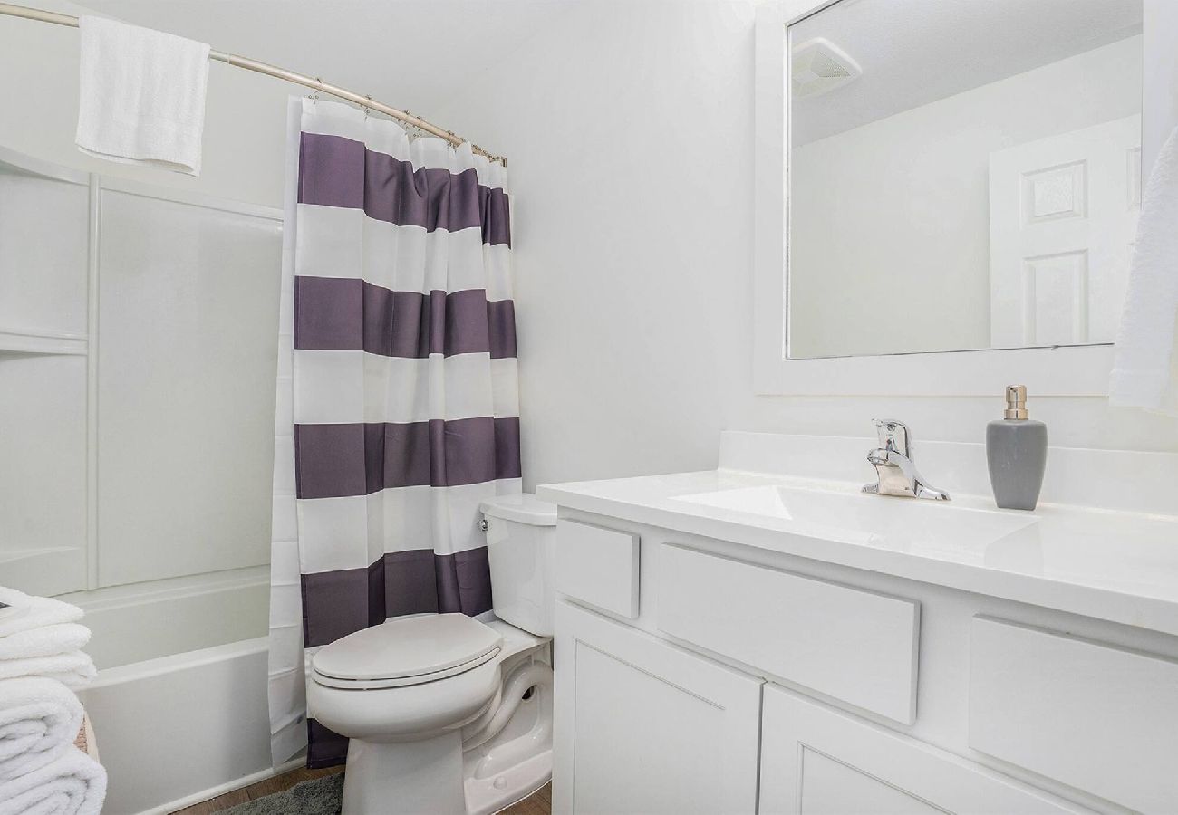 Basement bathroom with shower/tub combo and white vanity
