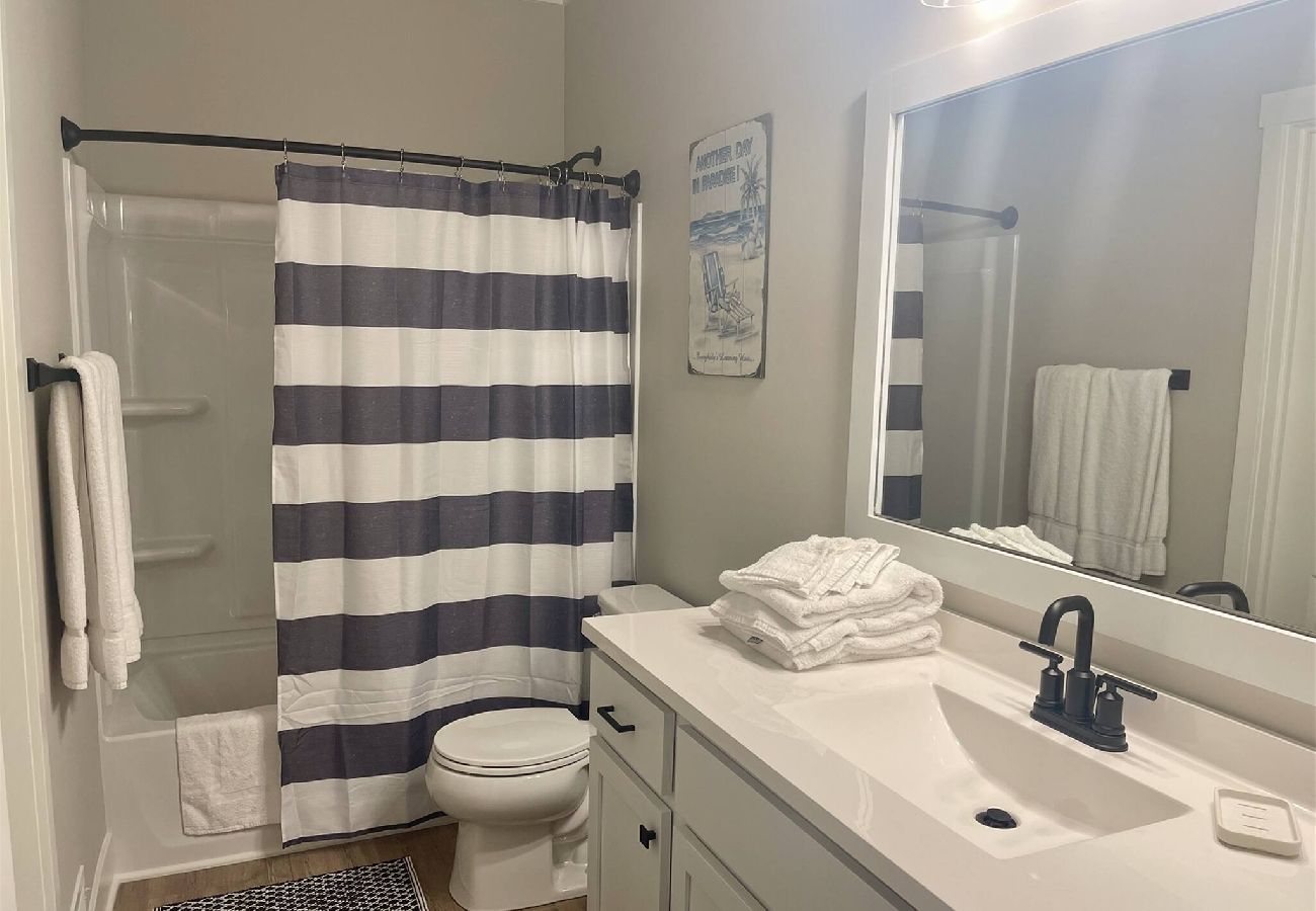 Main floor bathroom with white vanity, toilet and fresh towels