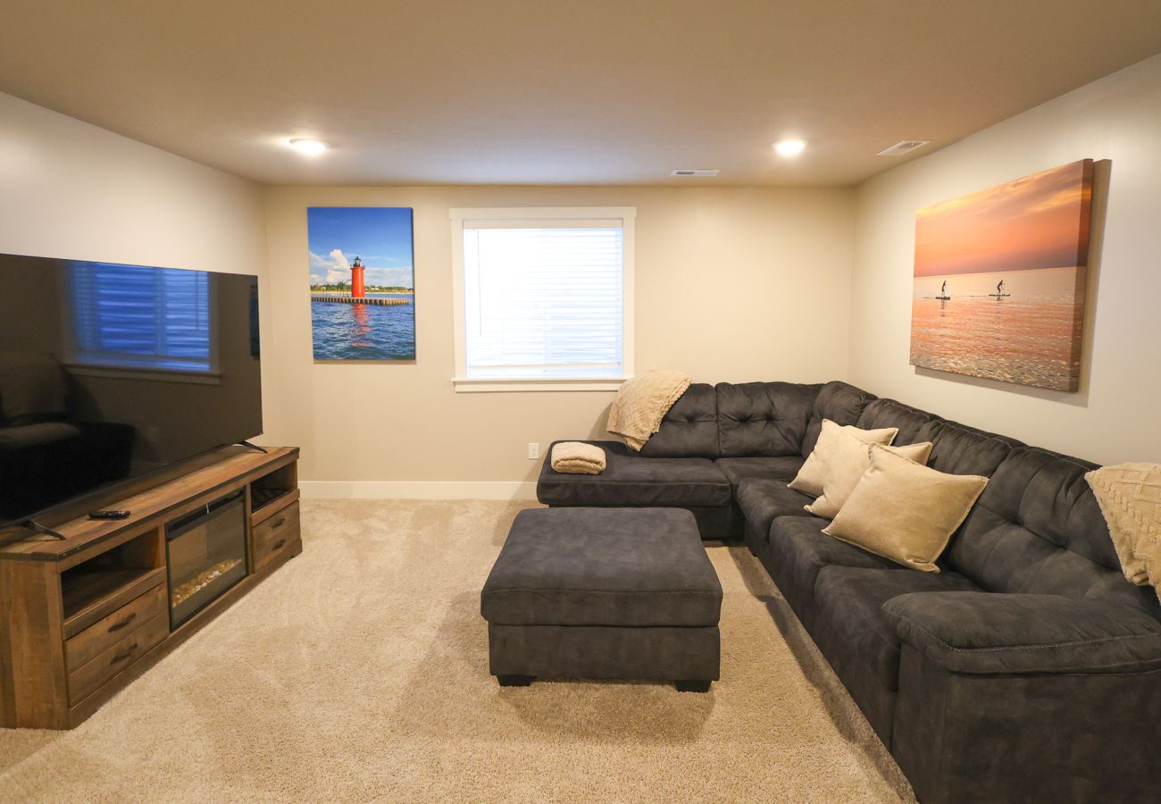 Basement living area with black sectional sofa and ottoman 