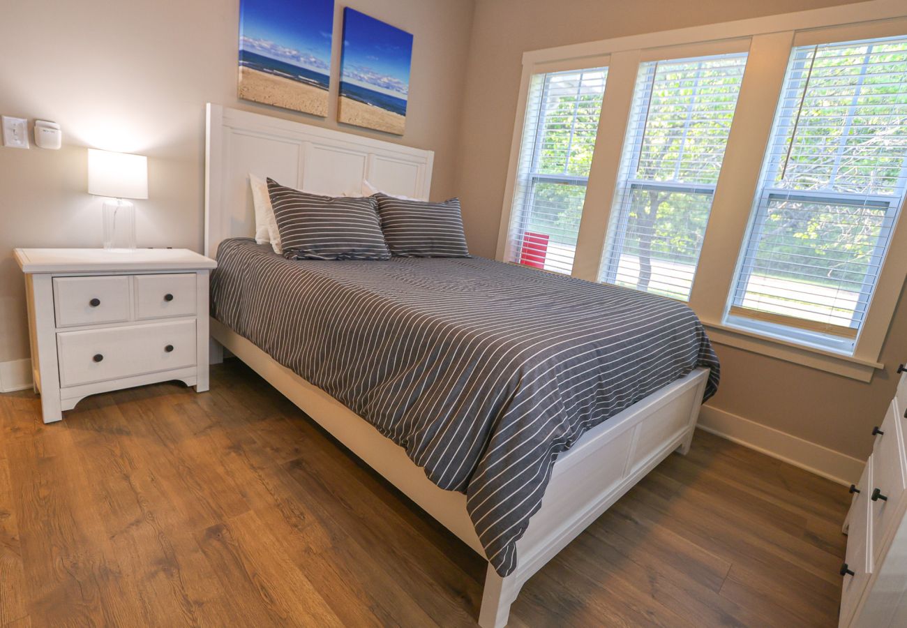 Main level queen bedroom with white furniture and stripped bedding