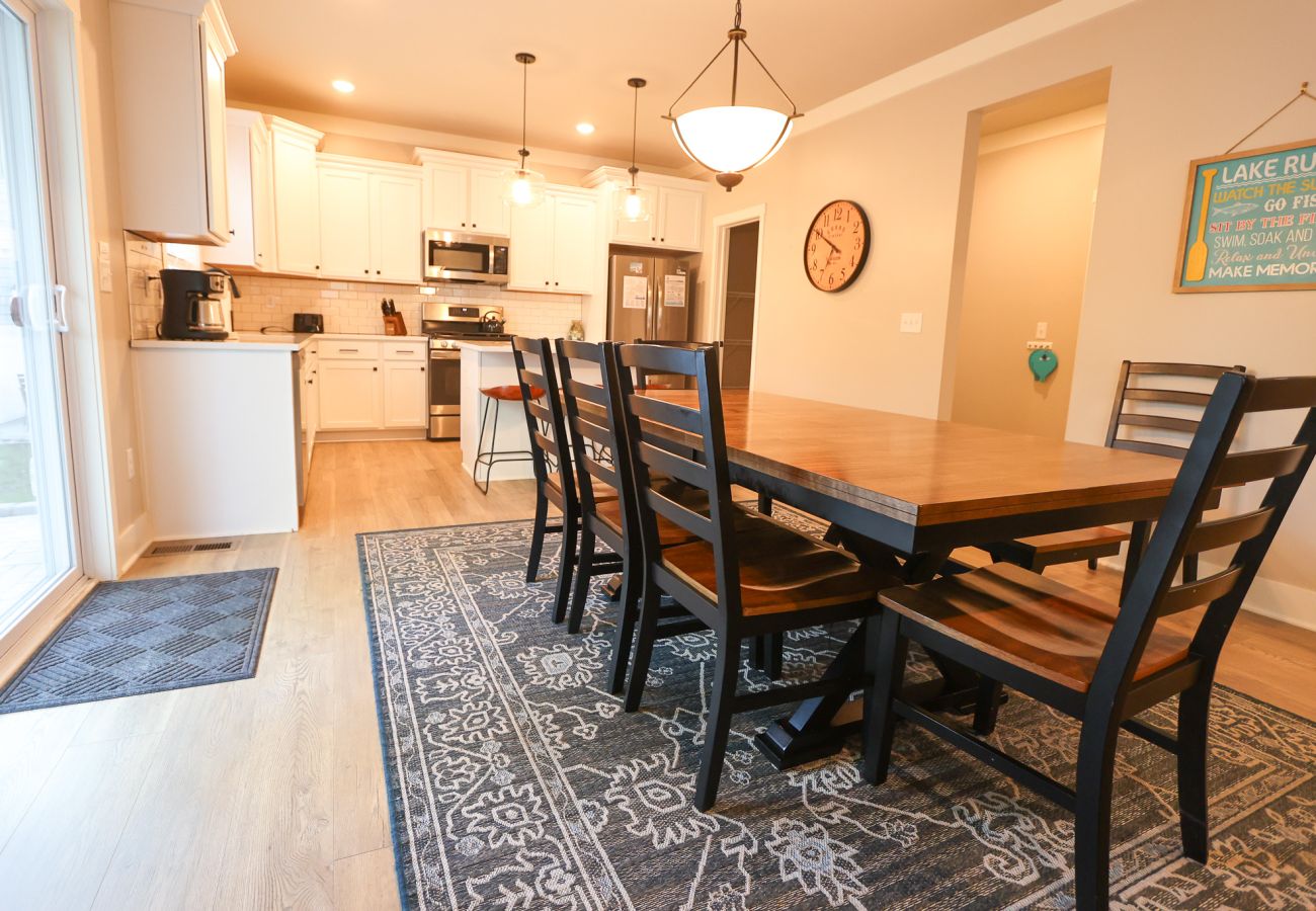 Kitchen with white cabinets, stainless steel appliances, center island, and wooden dining table and chairs 