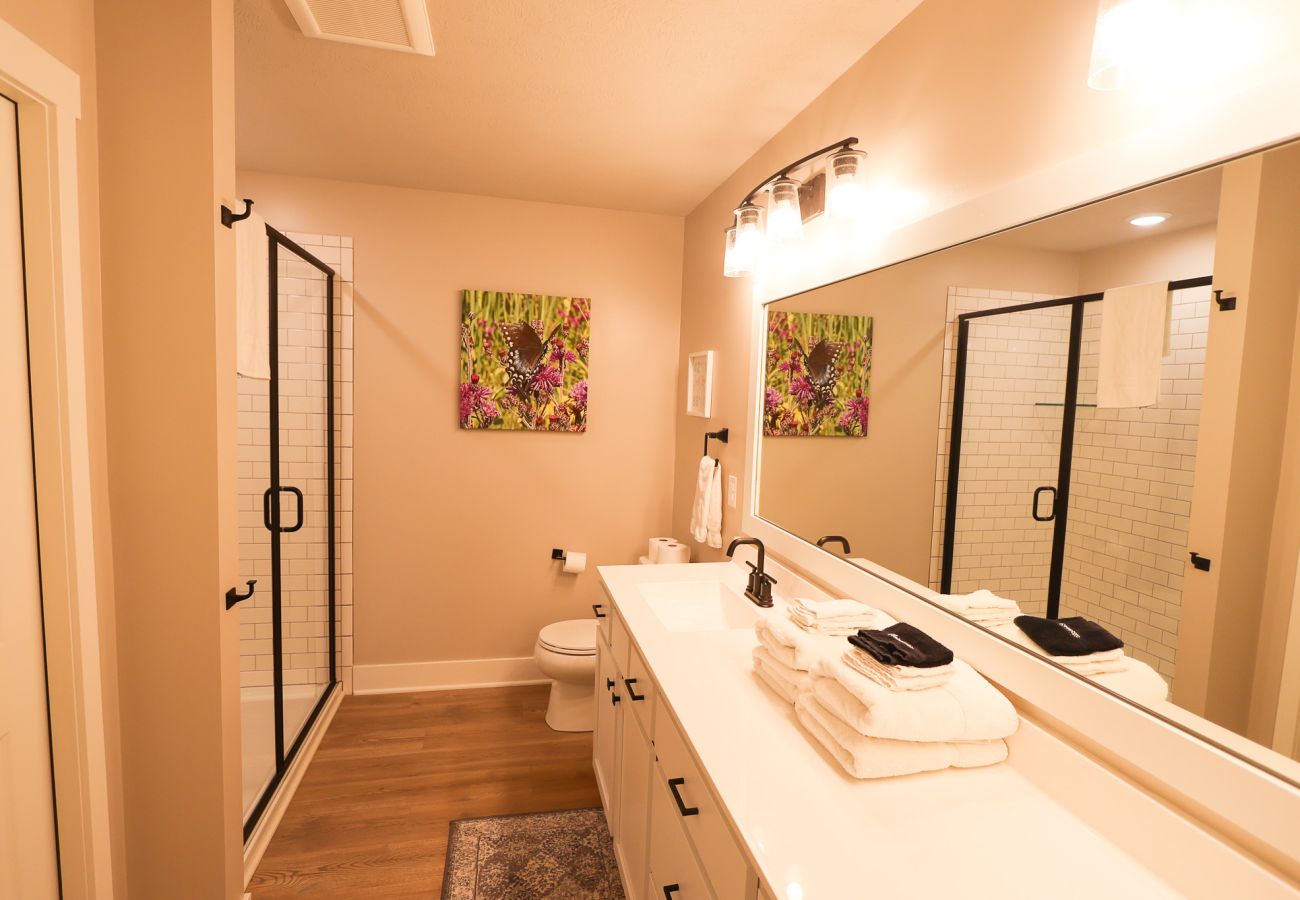 Primary bathroom with double vanity, walk-in subway tile shower, and black fixtures at Northside Retreat