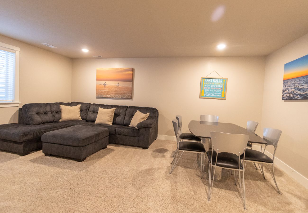 Basement living area with large sectional sofa and dining/game table at Northside Retreat 