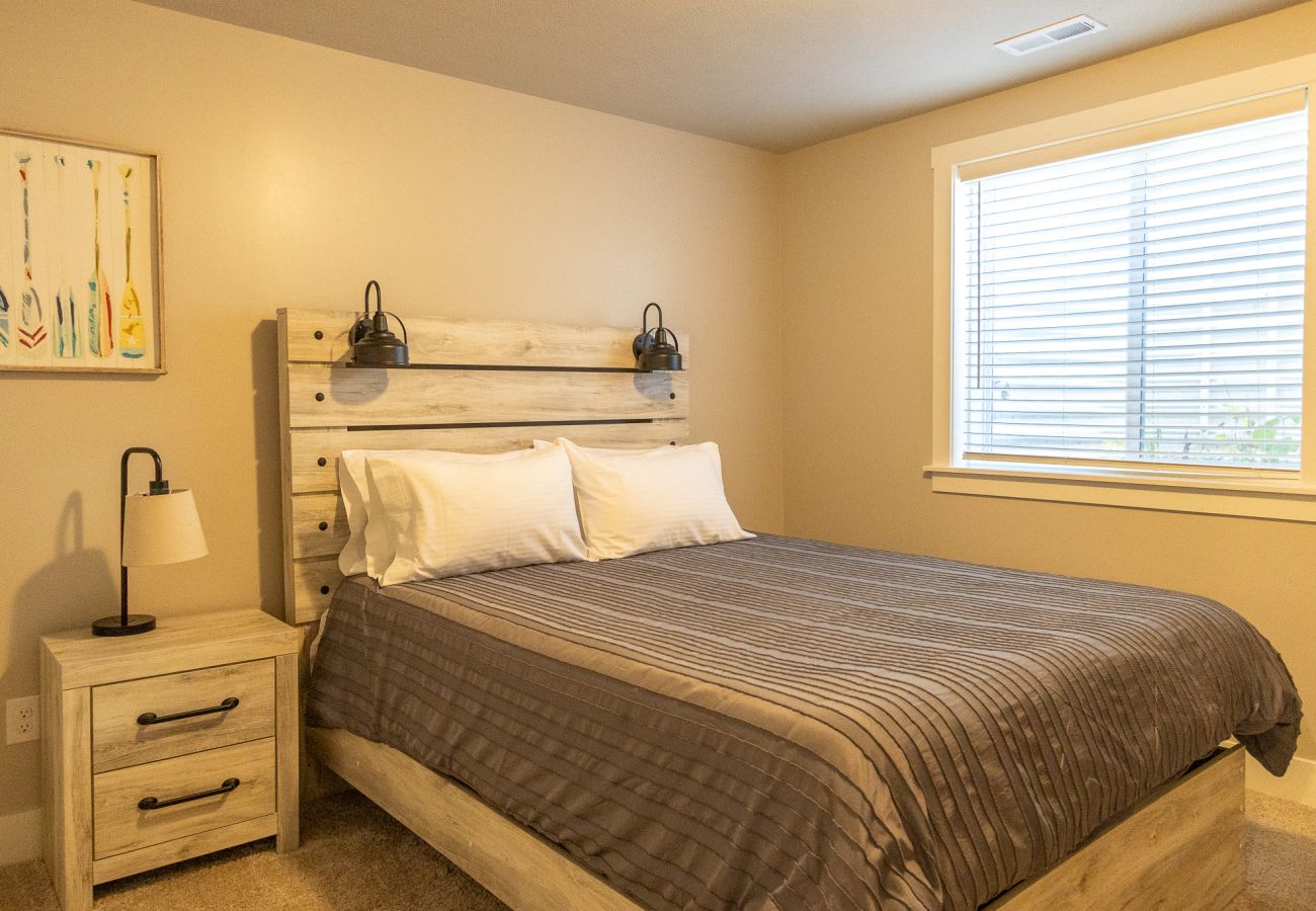 Basement queen bedroom with wooden bedframe and nightstand.
