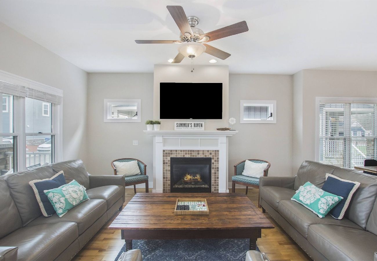 Living room with leather sofas, wooden coffee table, fireplace, and mounted TV