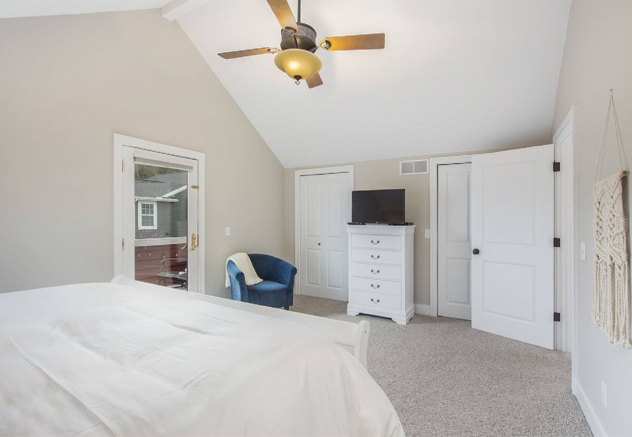 Primary bedroom with king bed, TV, chair, and patio Access in South Haven 