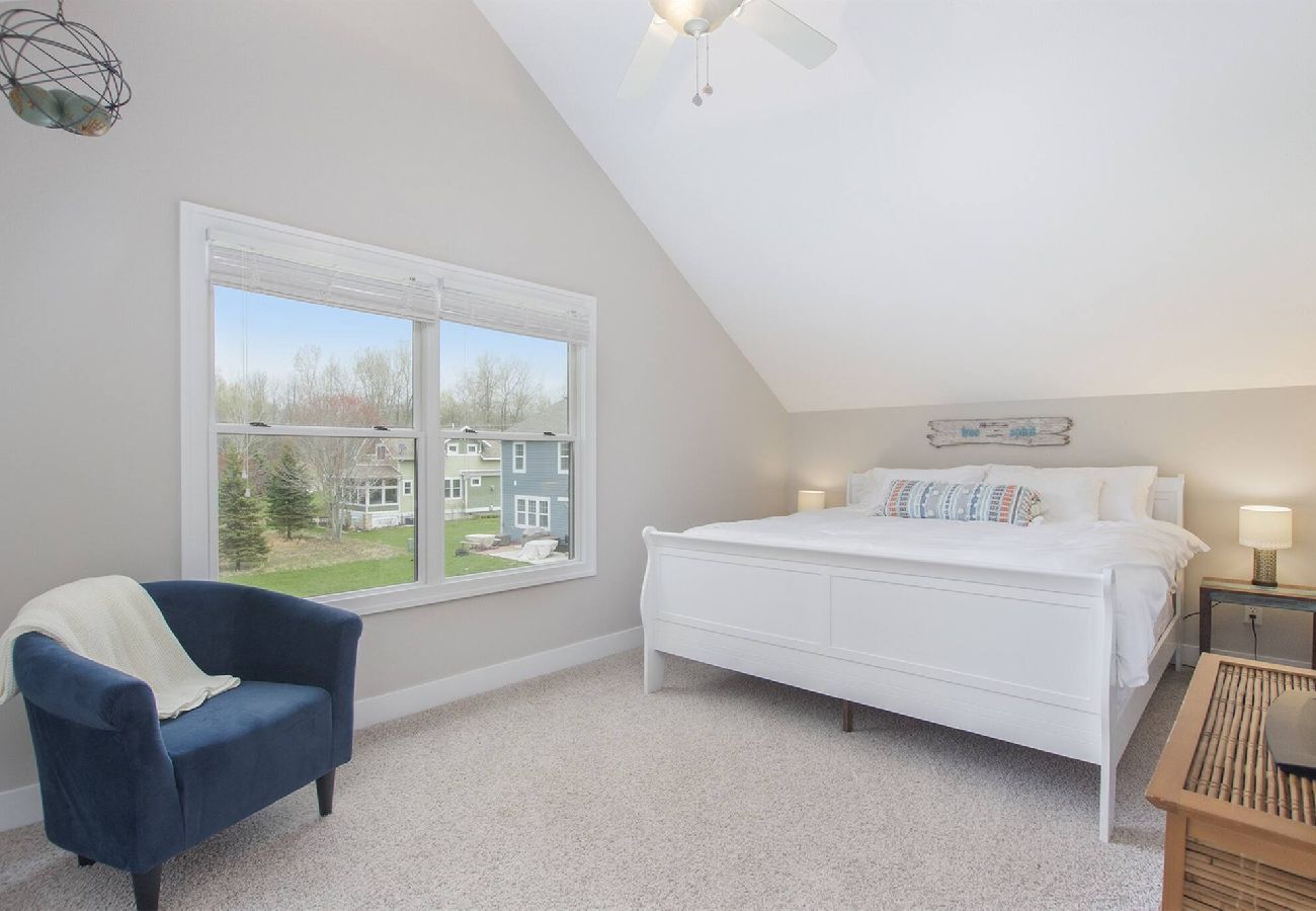 Light-filled bedroom with king bed and blue accent chair in South Haven