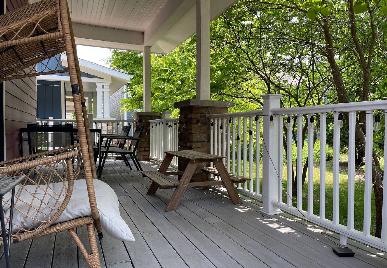 Covered porch with wicker seating, picnic table, and wooded view