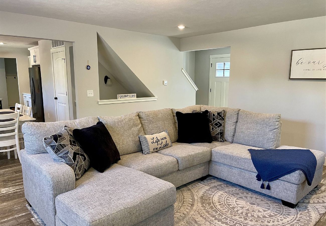Bright Living room with gray sectional sofa, and open layout leading to the kitchen and dining area