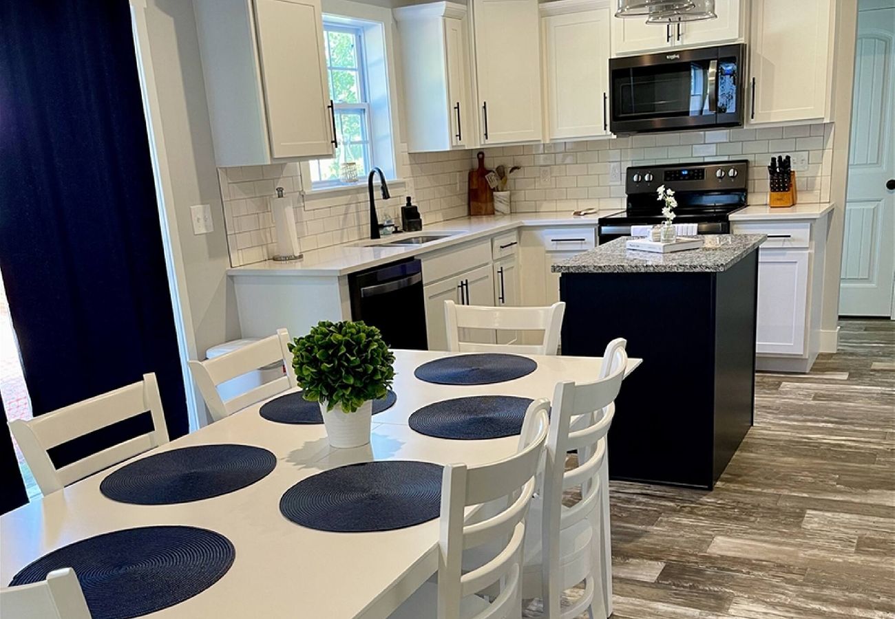 Bright modern kitchen with white cabinets, island, and a dining table set for six