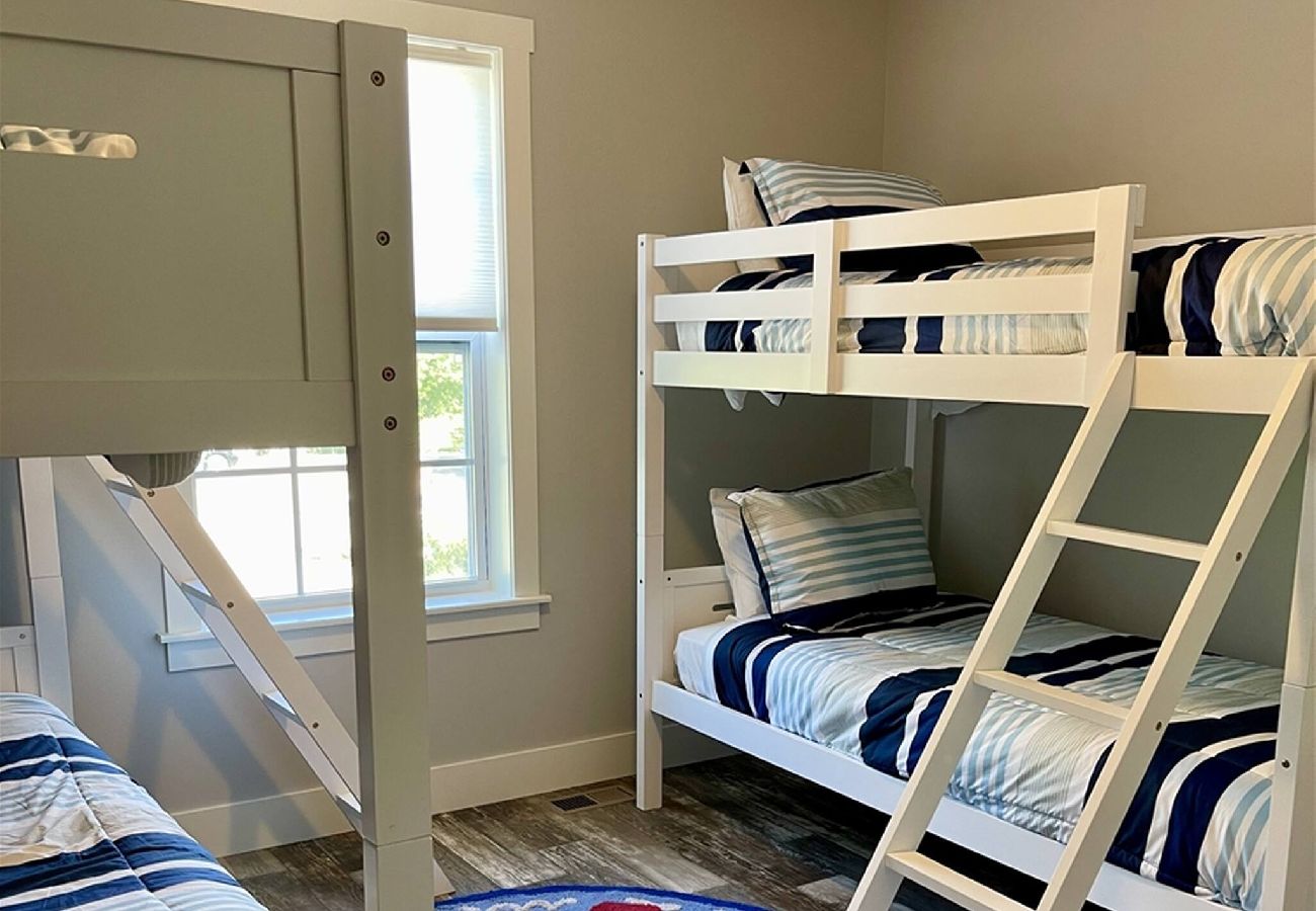 Bedroom with two white bunk beds, striped bedding, and a round nautical-themed rug