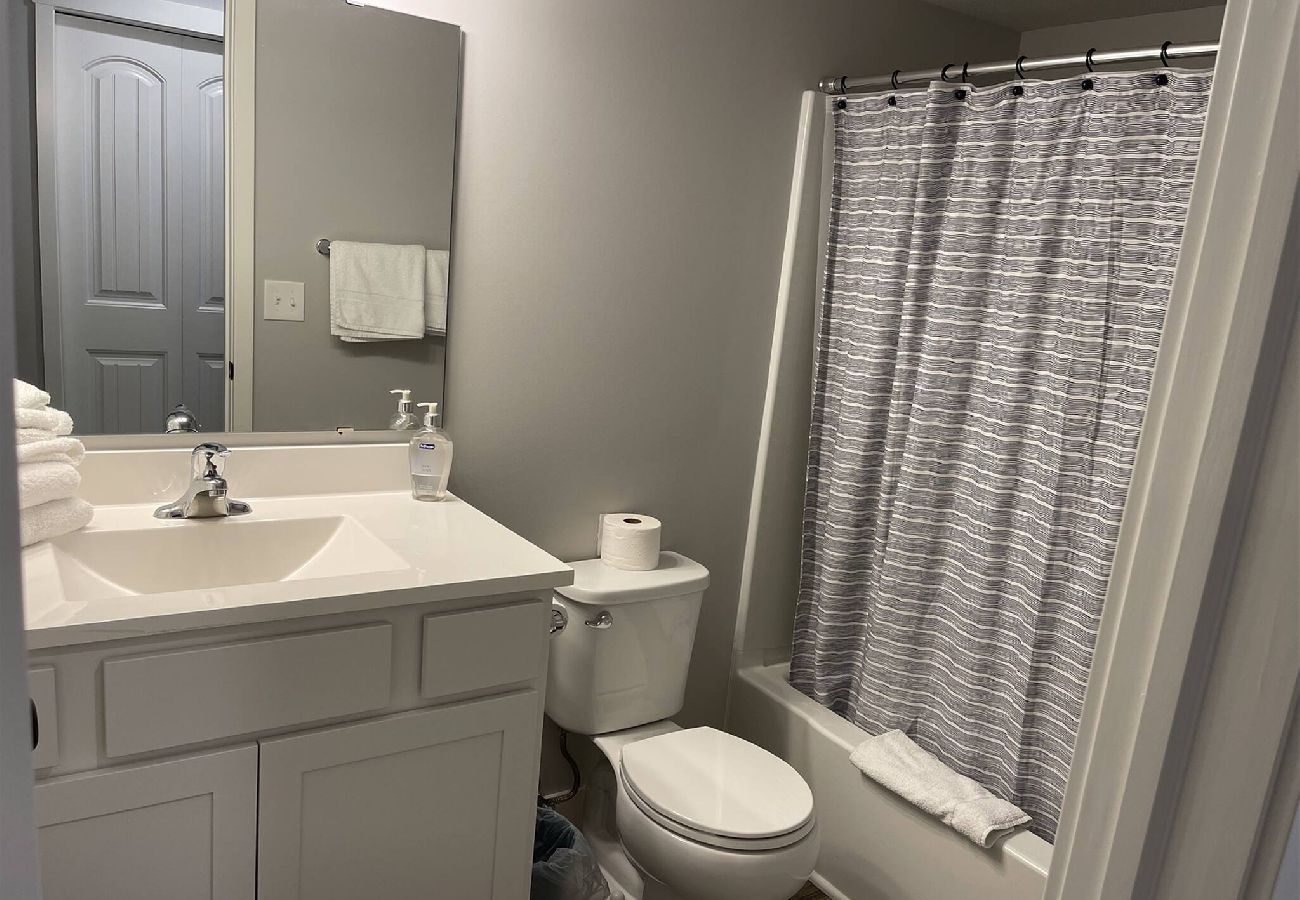 Basement bathroom, a white vanity, and shower/tub combo