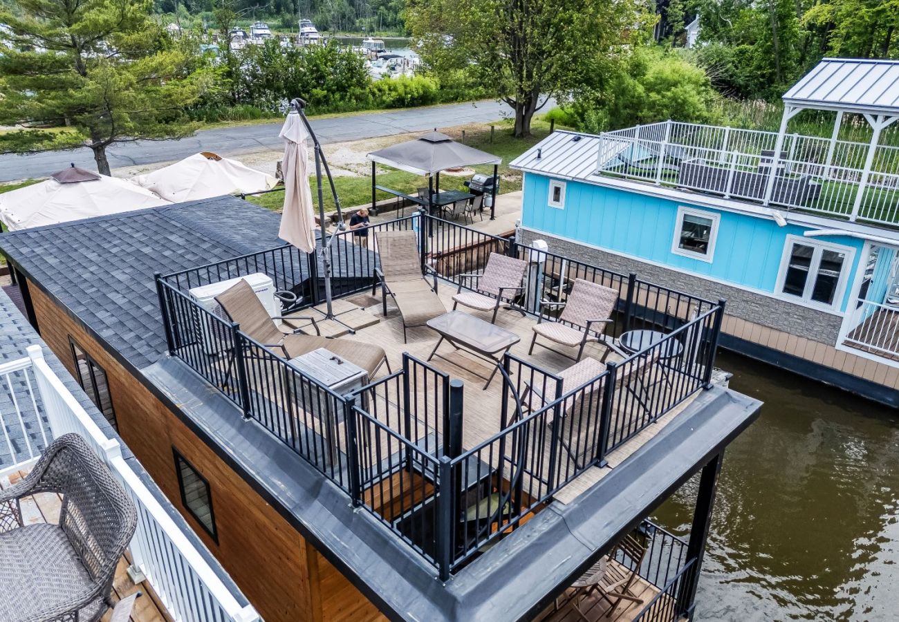 Rooftop deck at Shoreside Haven featuring lounge chairs, seating, and fenced railing overlooking the marina