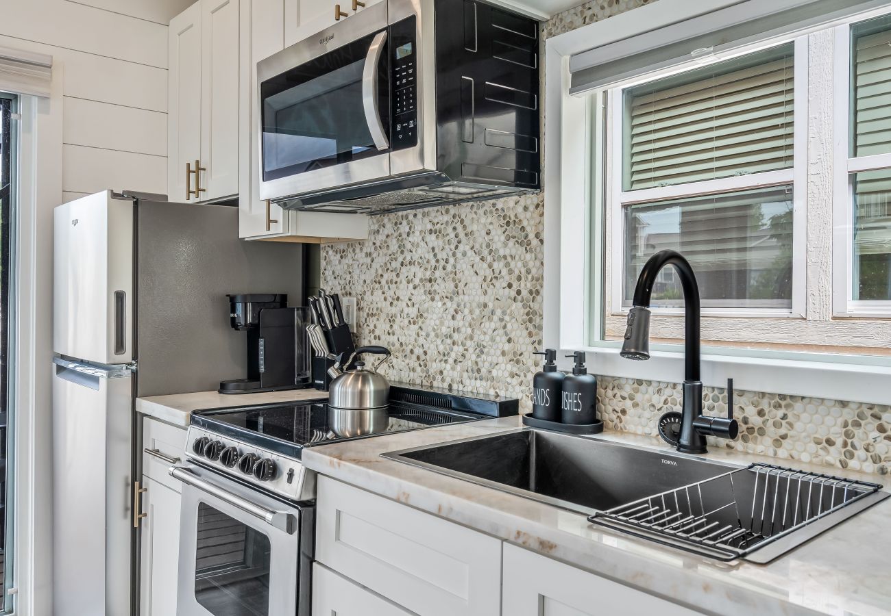 Compact modern kitchen at Shoreside Haven with stainless steel appliances, smooth-top stove, microwave,  and deep sink