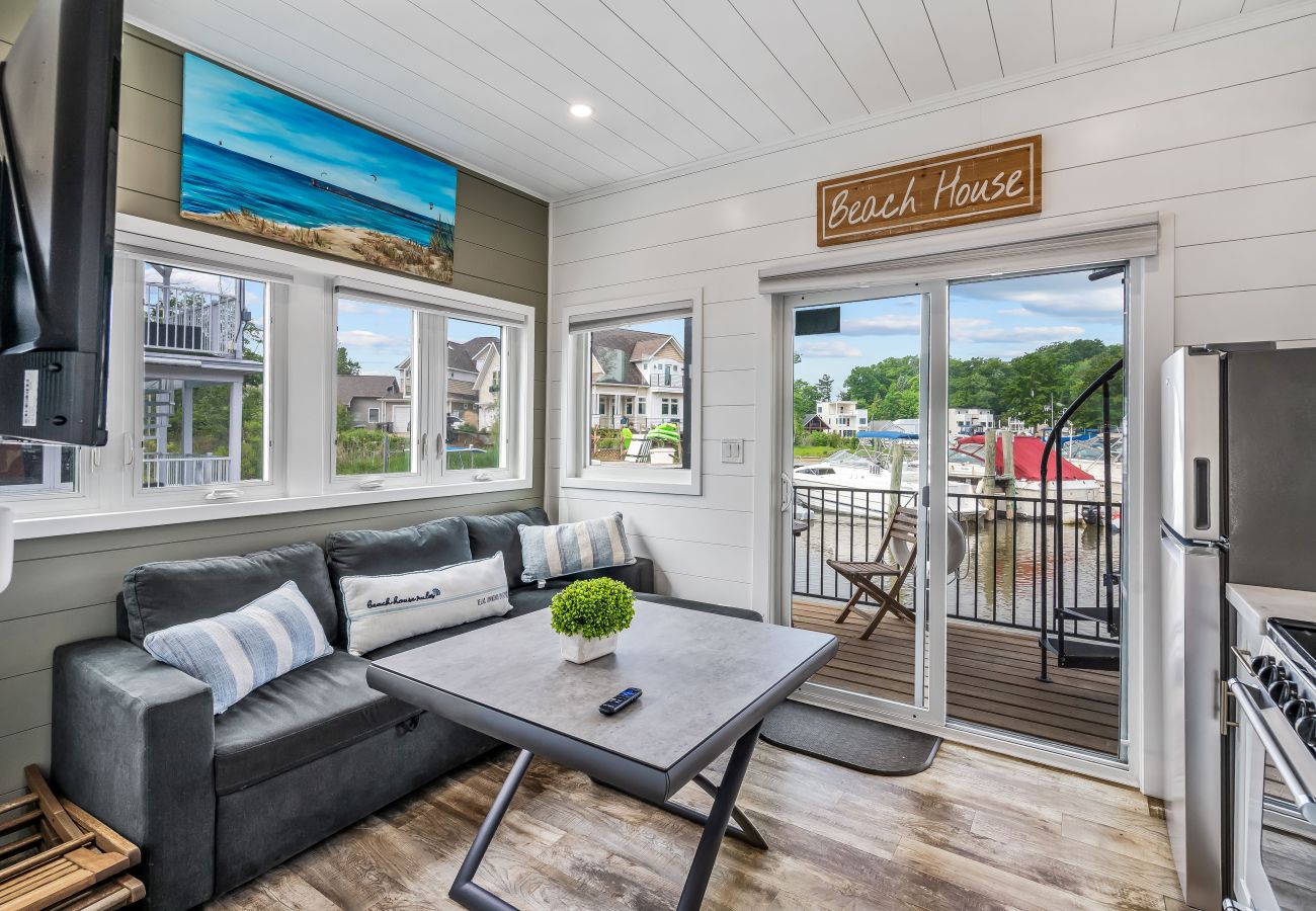 Living area at Shoreside Haven with sofa, dining table, large windows, sliding doors to the deck , and views of the marina