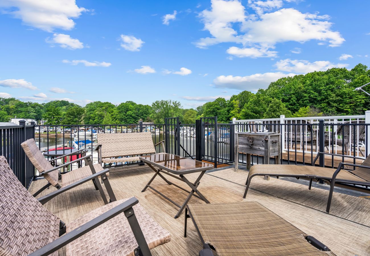 Rooftop deck at Shoreside Haven featuring lounge chairs, seating area, and views of the marina and tree-lines shoreline.