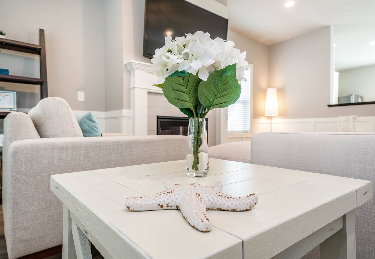 Bright living room with light sofas,a white coffee table, and a fireplace in a modern open-concept home