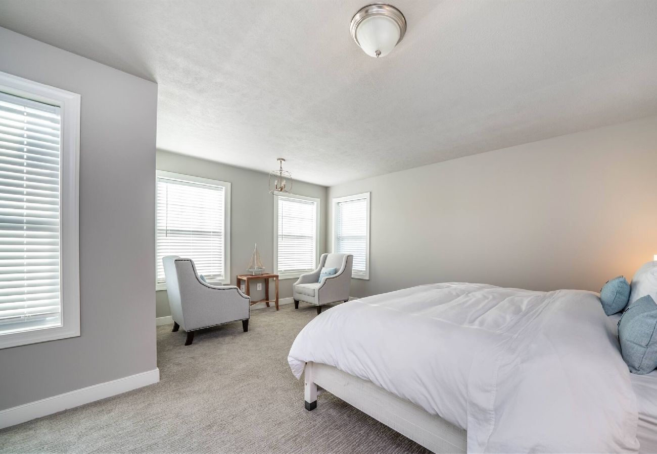 Primary bedroom with a king bed, soft coastal accents, and a bright sitting area