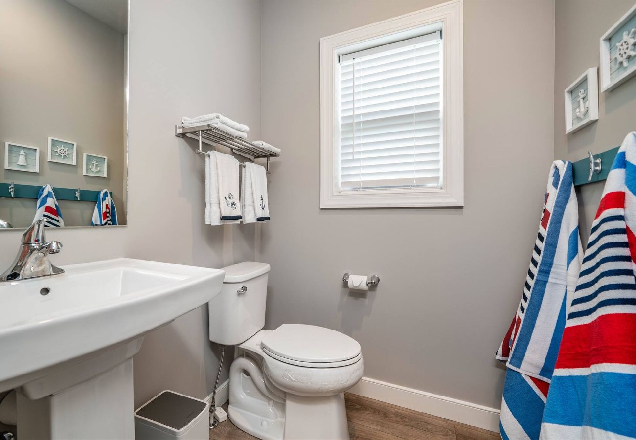 Half bathroom with a pedestal sink, toilet, and wall-mounted towel rack