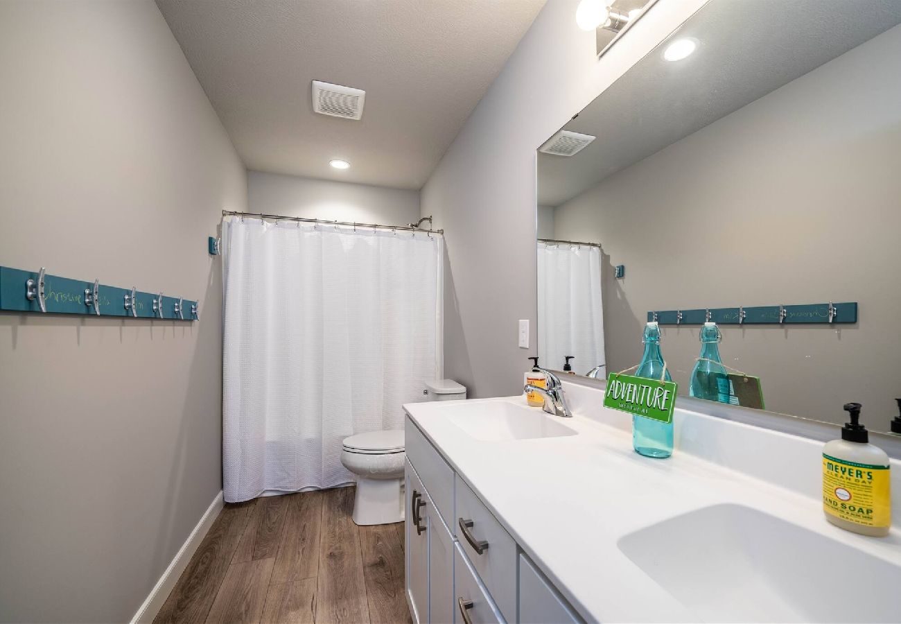 Clean bathroom featuring a white vanity, large mirror, wood-look flooring, and shower tub combo 