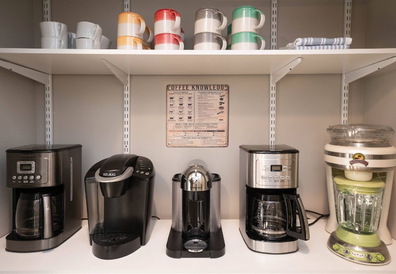Cofee station featuring drip coffee makers, a Keurig, a Nespresso machine, and colorful mugs