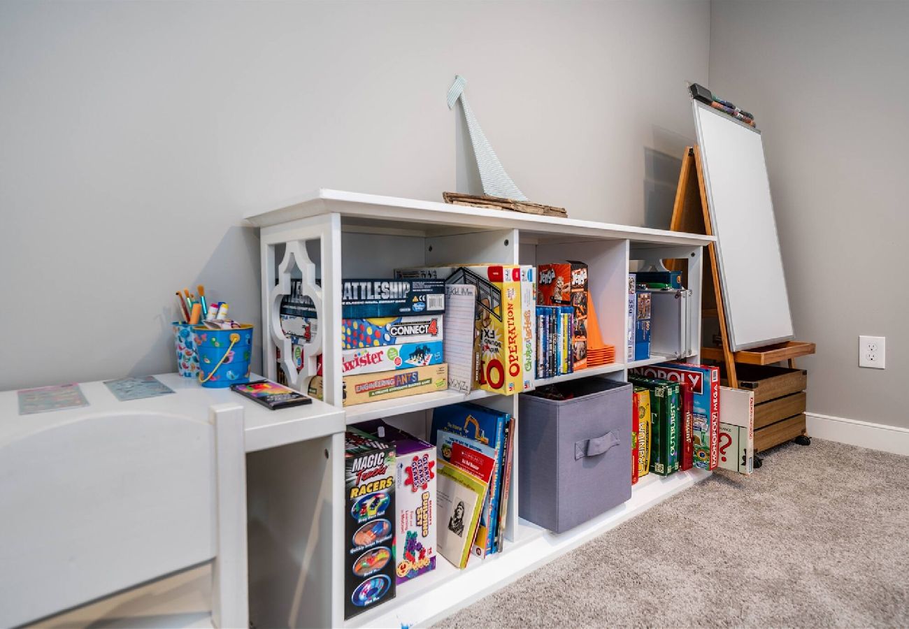 Basement play area featuring shelves filled with board games, puzzles, art supplies.
