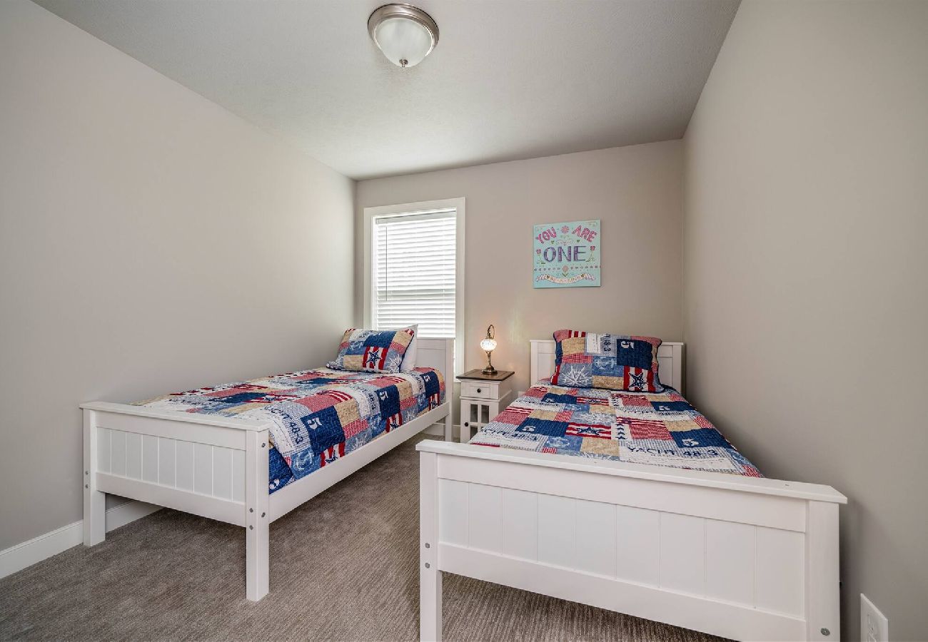 Bedroom with two white twin bed, matching patriotic patchwork quilts, and a shared nightstand