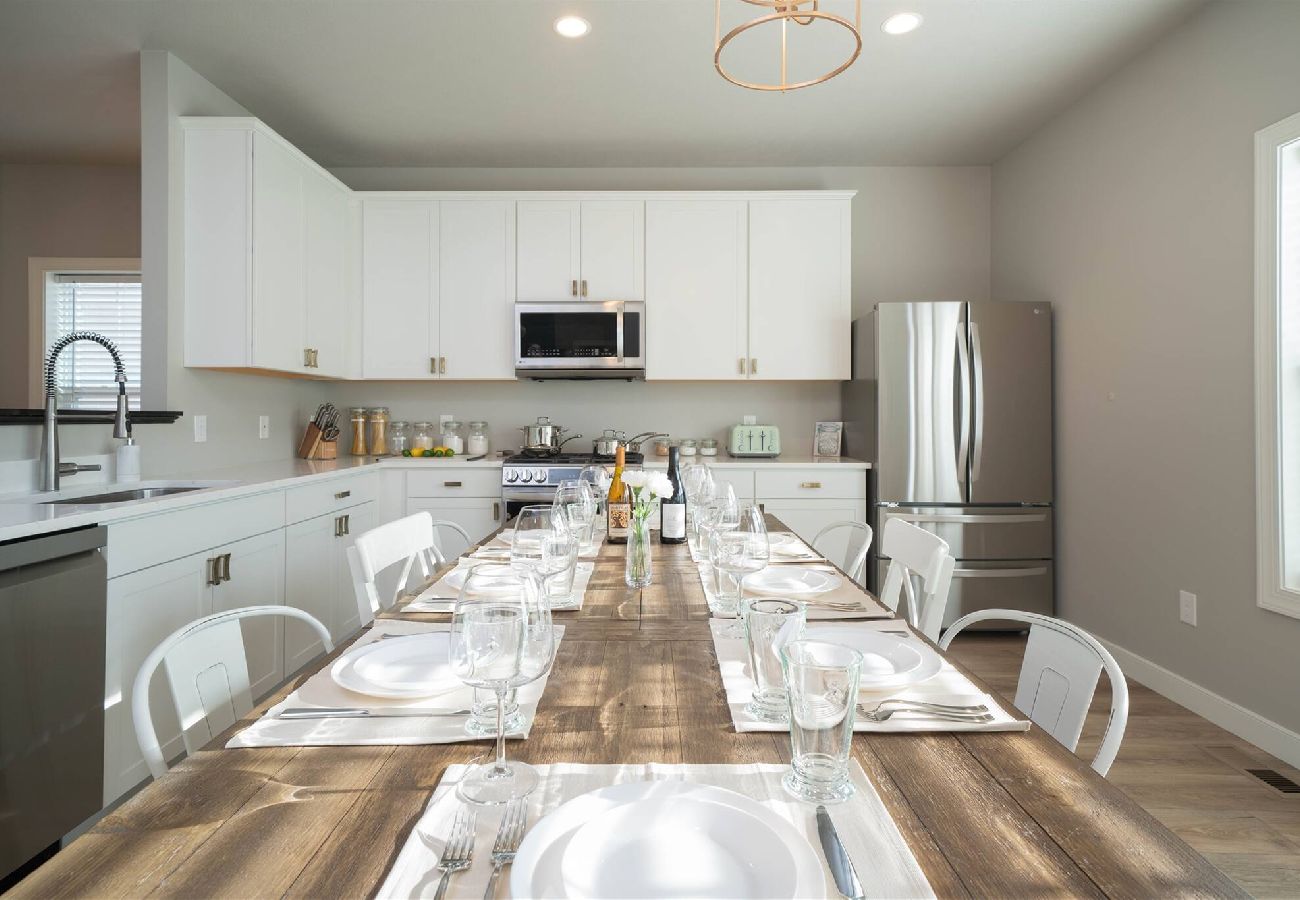 Bright kitchen with white cabinets, stainless steel appliances, and a large farmhouse-style dining table