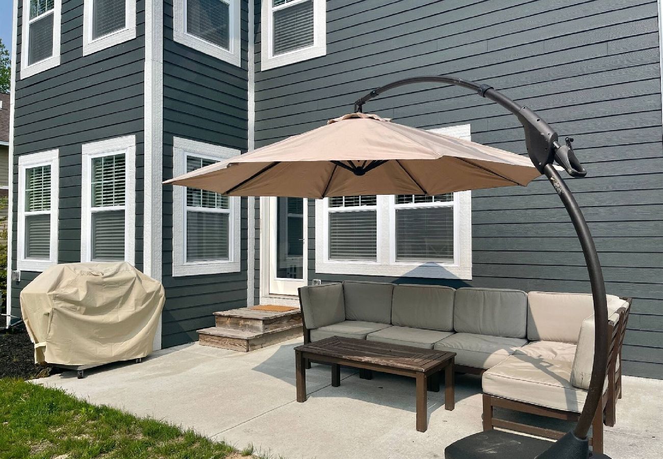 Backyard patio with a cushioned sectional sofa, and  large umbrella, will with cover