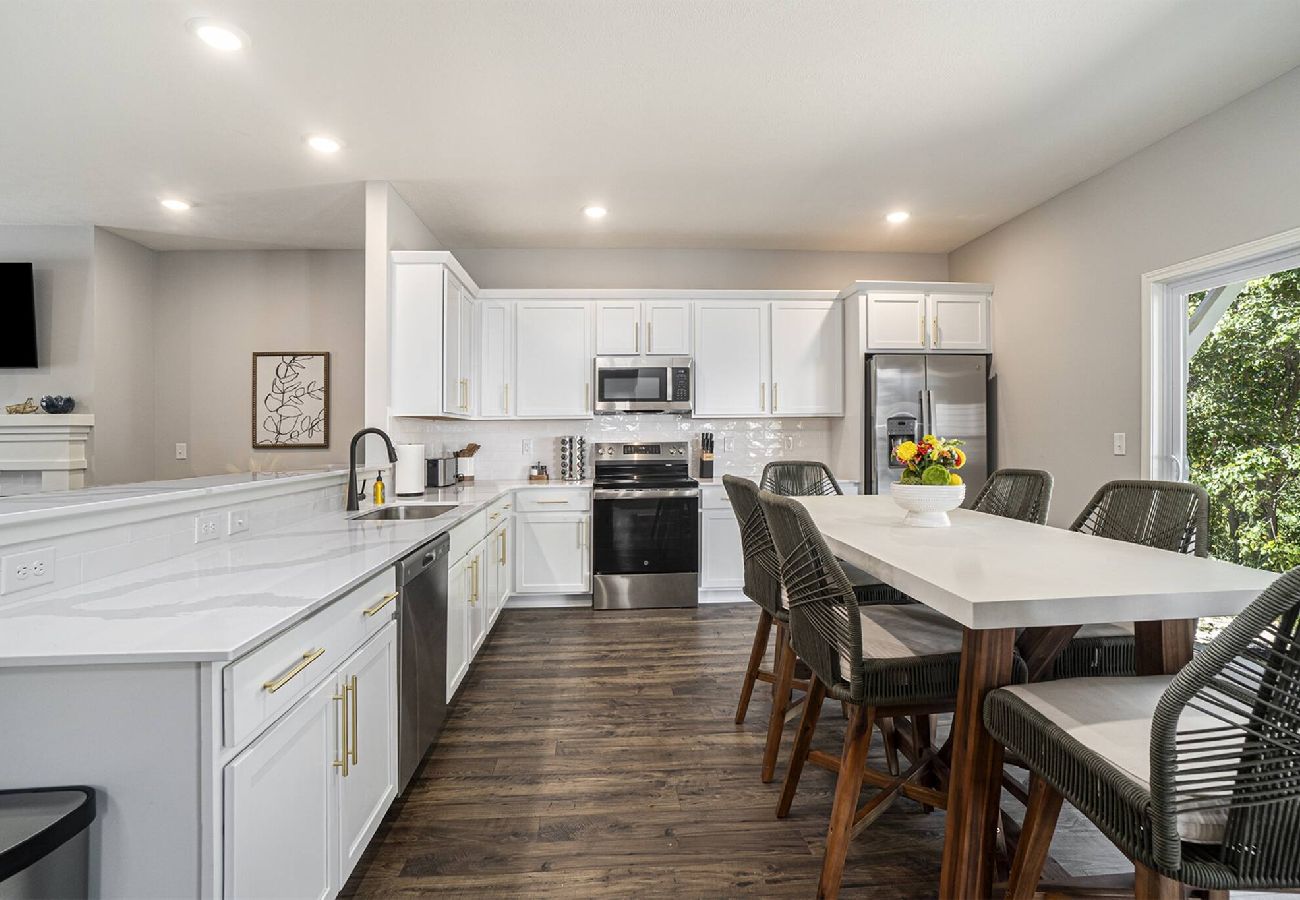 Bright kitchen with white cabinets, stainless steel appliances, and dining table 