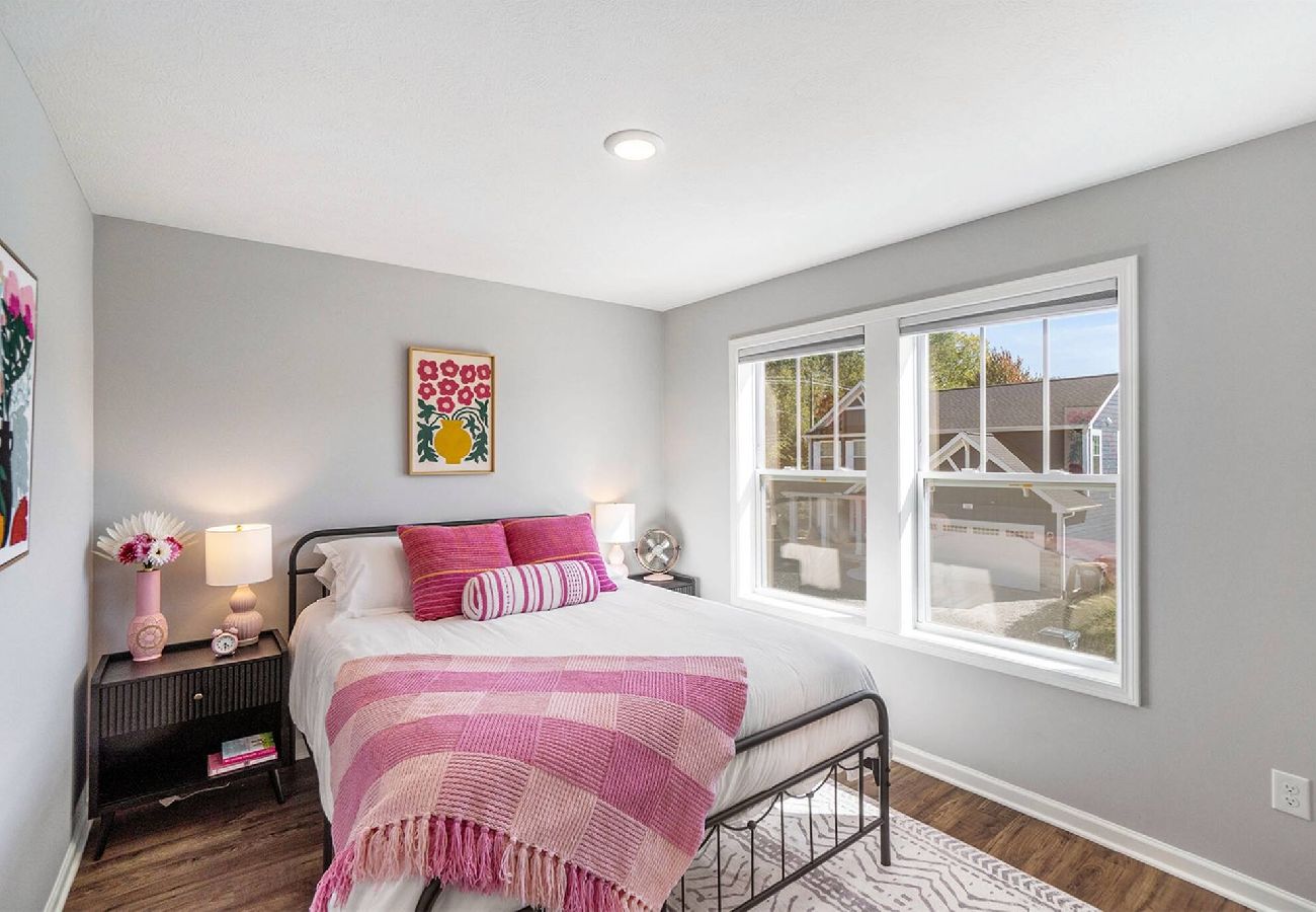 Bedroom with queen size bed ,pink accents and large windows