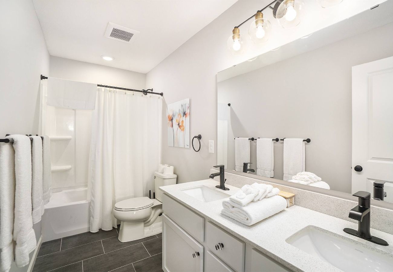 Bathroom with double-sink vanity, white shower, and fresh towels