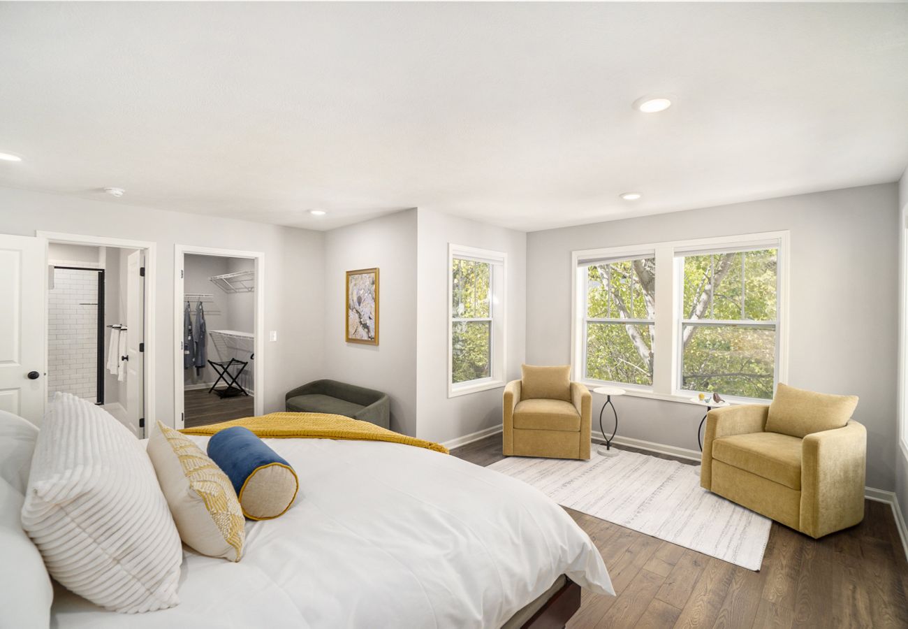 Spacious primary bedroom with king bed, seating area, and walk-in closet 