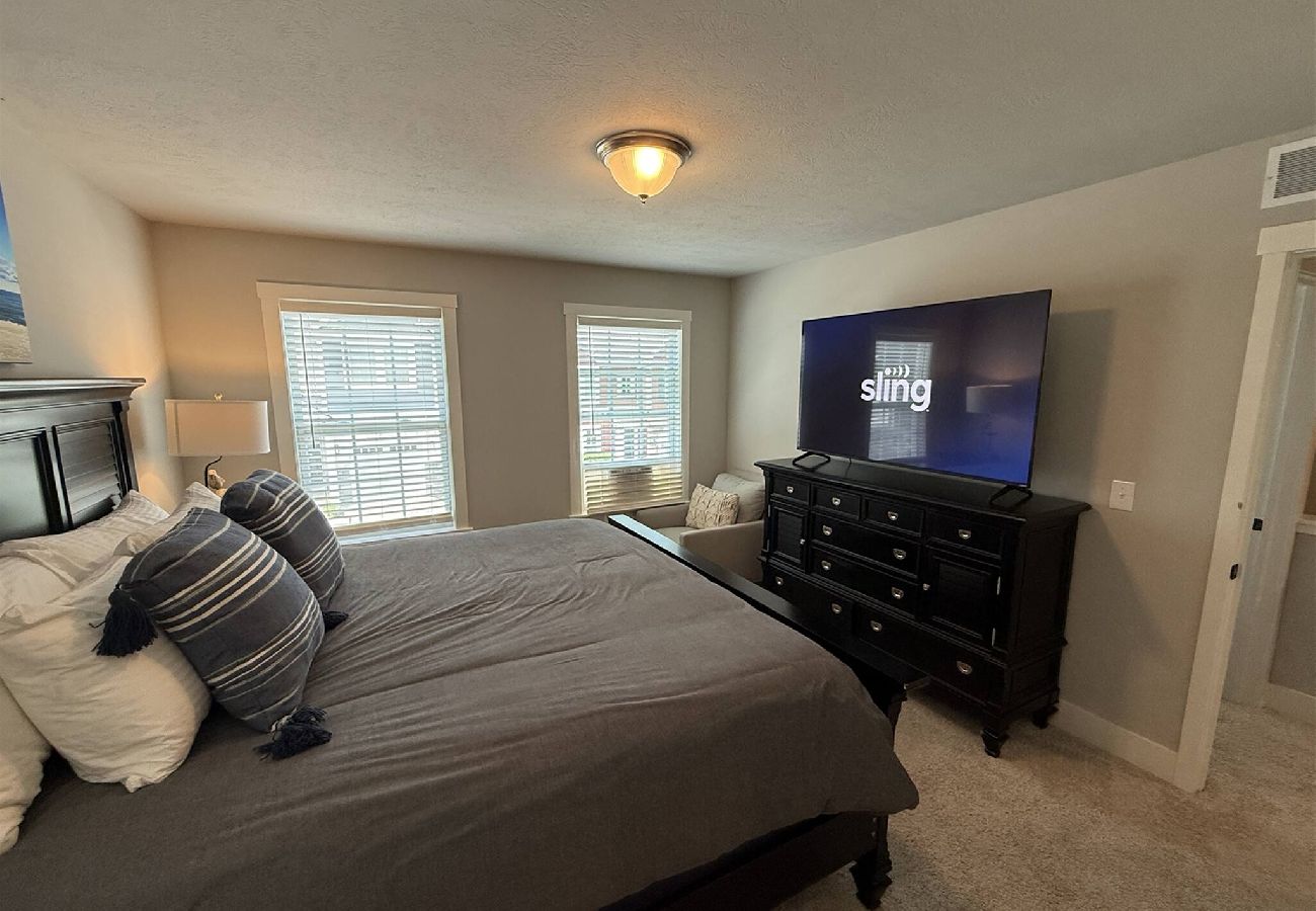 Bedroom with king bed, dresser, and large TV