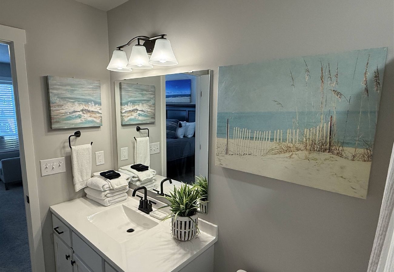 Master Bathroom with white vanity, modern fixtures, and beach–themed art work in South Haven