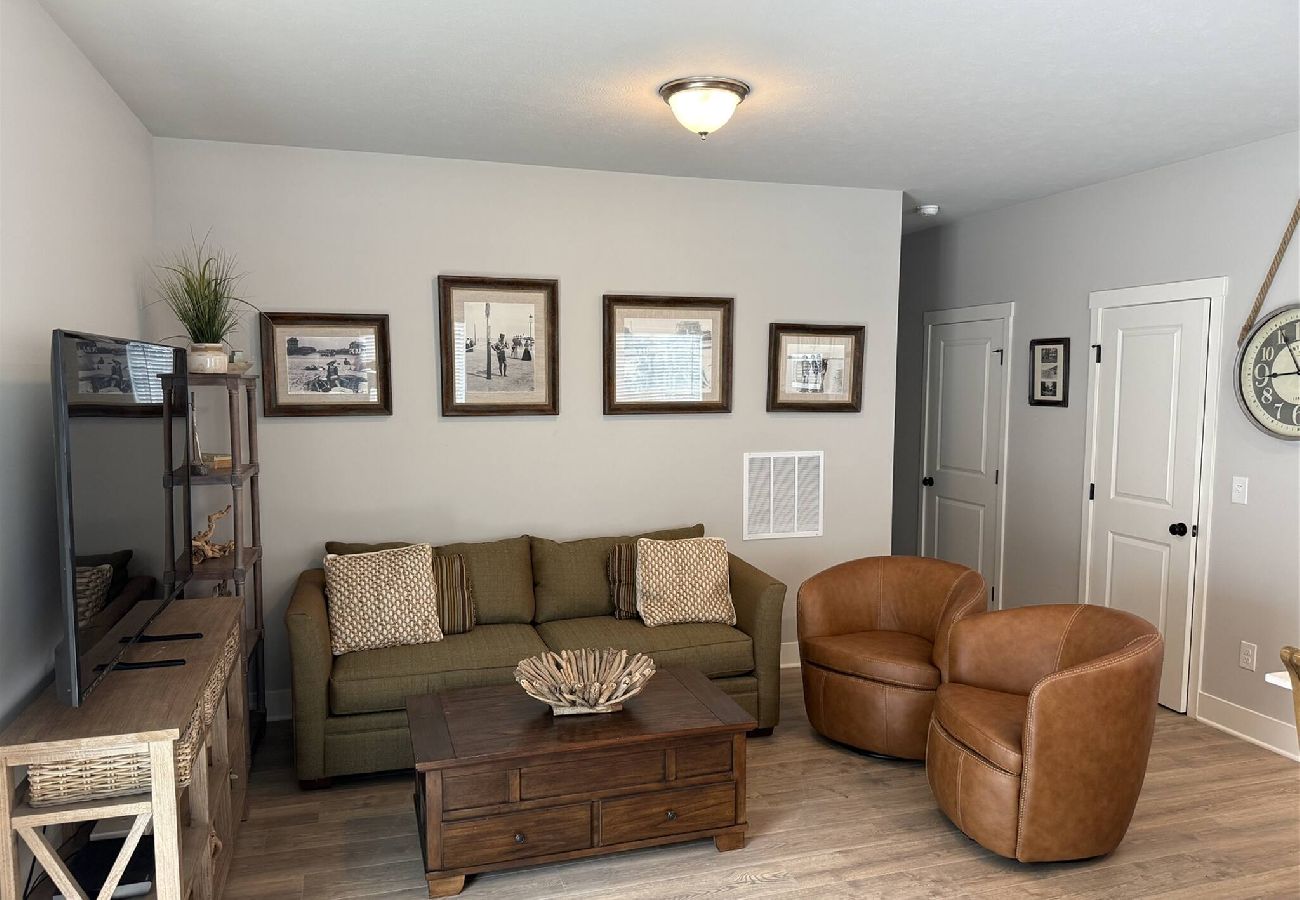 Vacation rental living room with sofa, leather chairs, and rustic decor