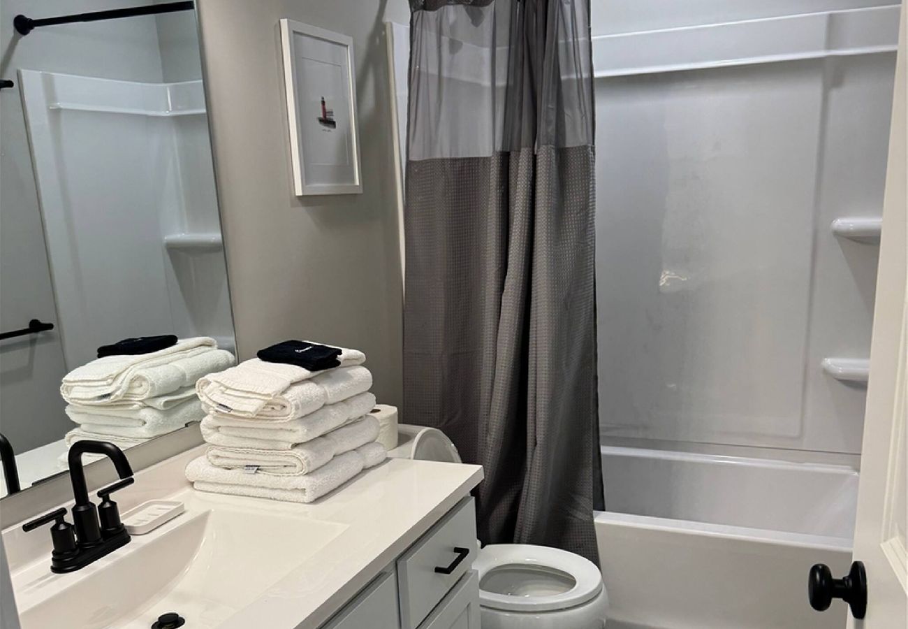 Bright modern bathroom with white vanity, shower and tub comb, and fresh towels, South Haven,MI